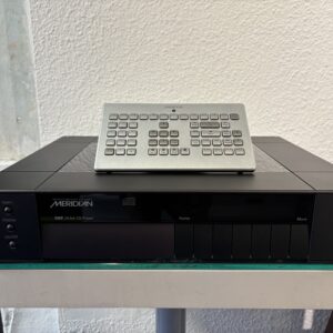 Meridian G07 24-bit CD player on a glass shelf with a silver keypad-style remote on top.
